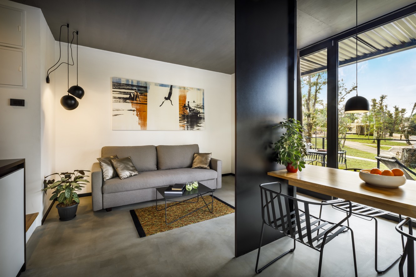 Modern living and dining area with large windows overlooking greenery at Aminess Younique Gaia Green Villas in Njivice.