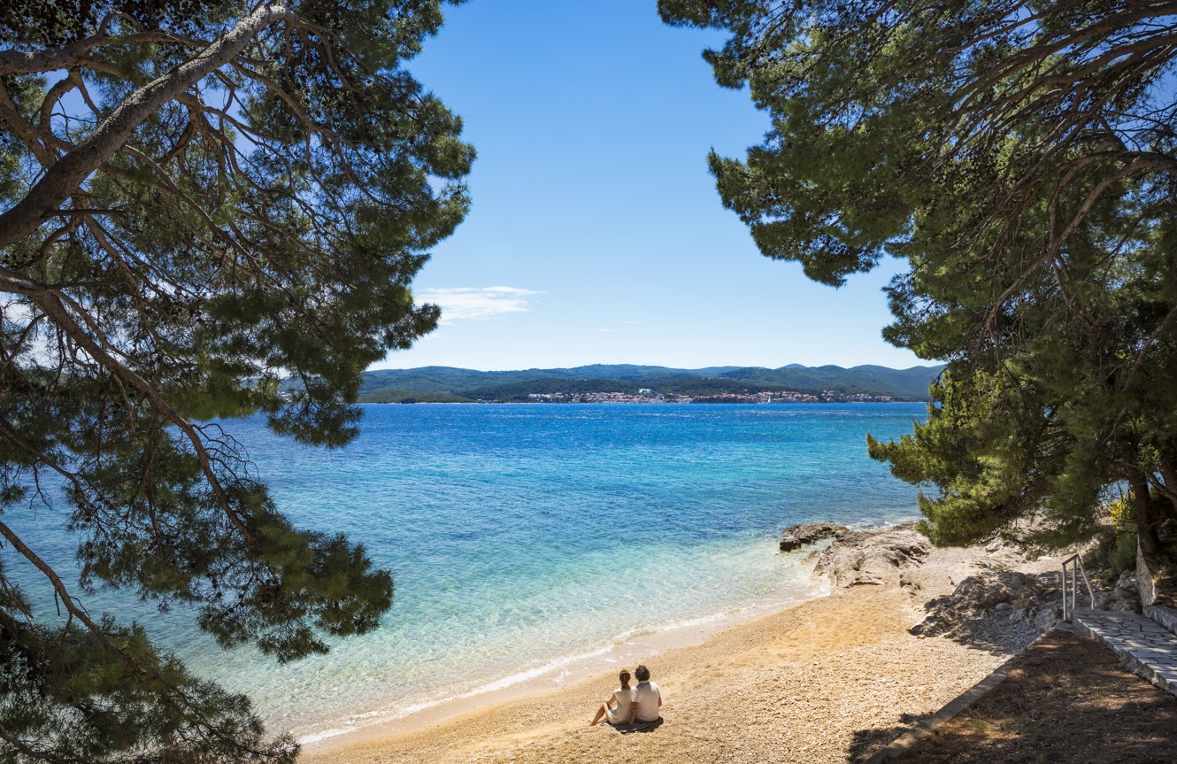 Couple relaxing at the beach near the Aminess Vival Grand Azur Hotel, overlooking the azure blue sea on Peljesac in Dalmatia.
