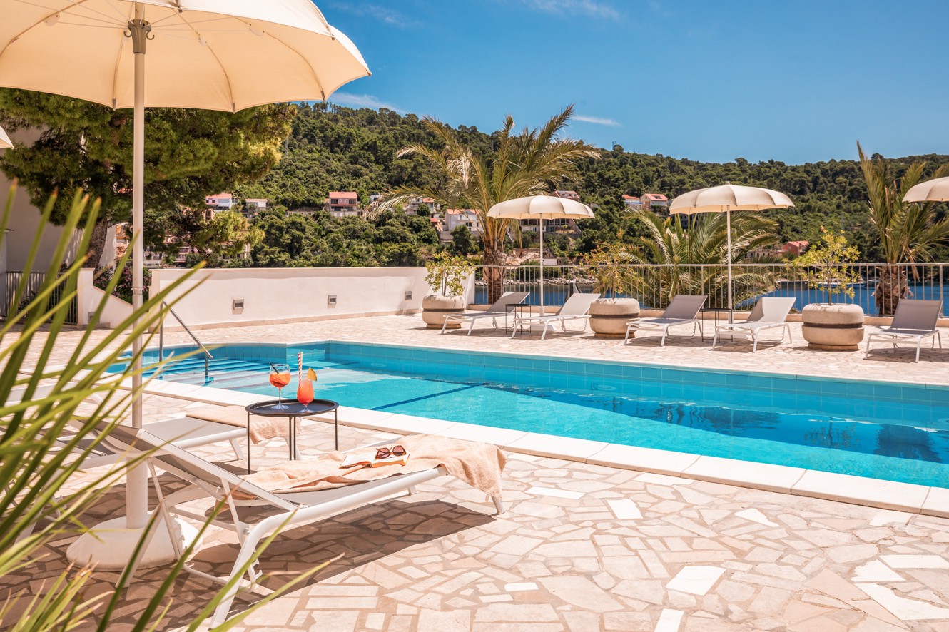 Pool area at Aminess Lume Hotel with sunbeds and Mediterranean greenery
