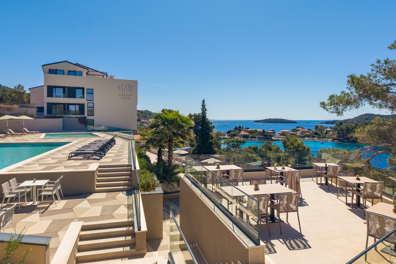 Poolbarterras van Aminess Alfir Hotel met zwembaden en uitzicht op zee.