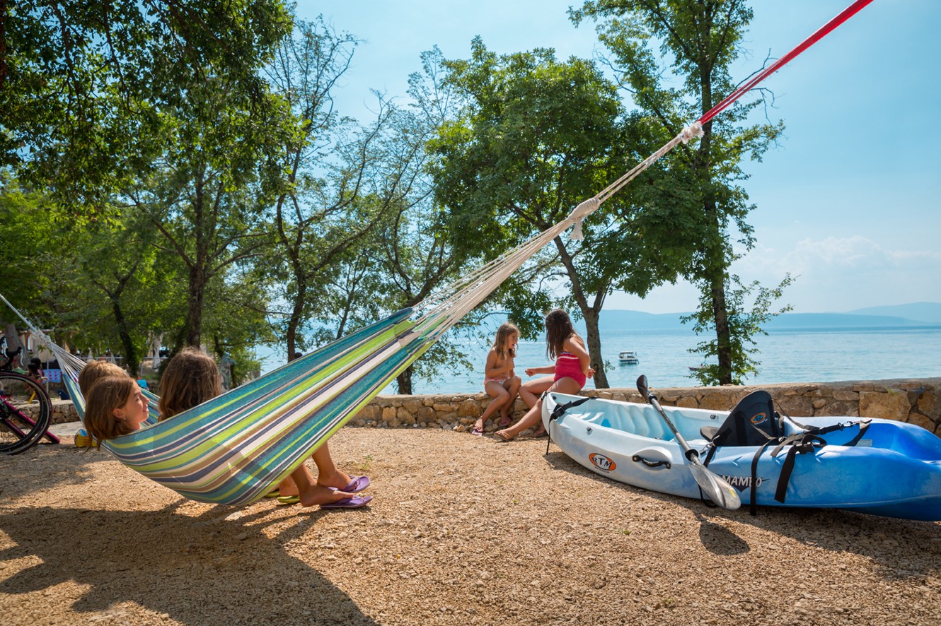 Območje za sprostitev z mrežami in kajaki pod drevesi v Aminess Style Camping Atea Resort.