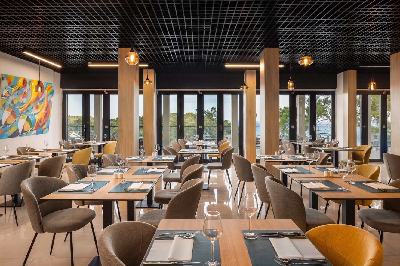 Restaurant van Aminess Alfir Hotel met gedekte tafels en uitzicht op zee.