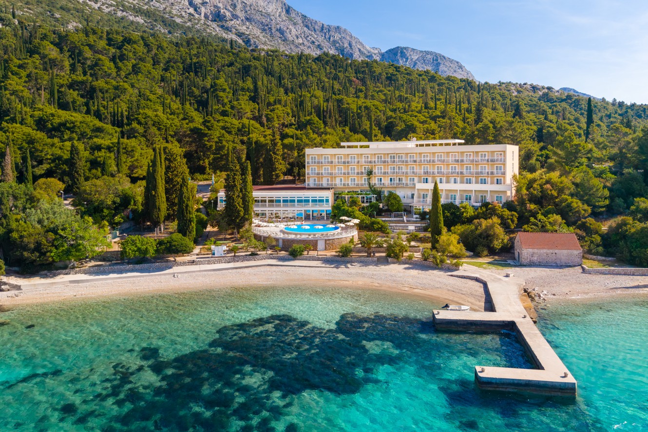 Aerial view of Orsan Maradiso Hotel by Aminess beside the sea and forested hills.
