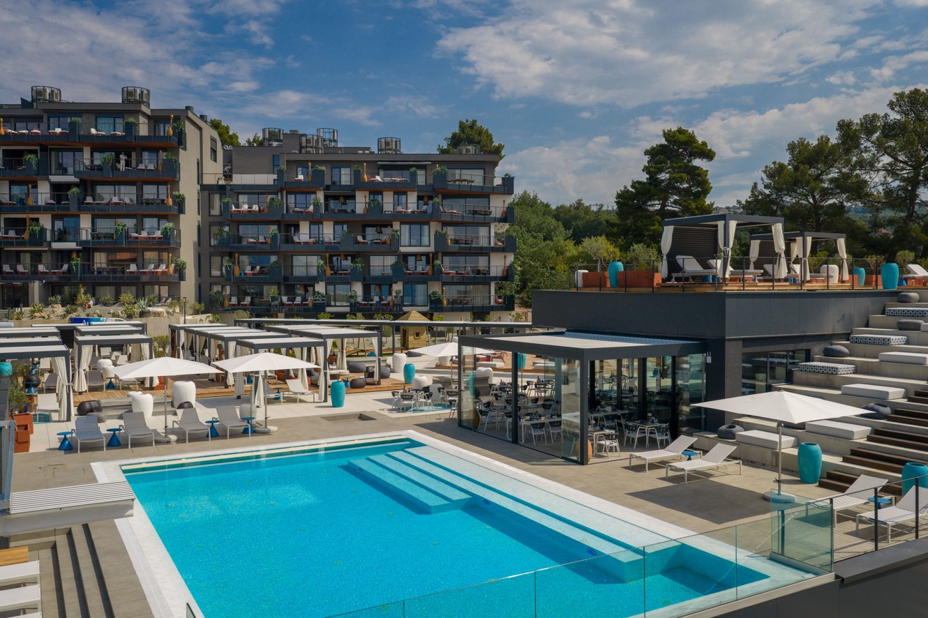 Vanjski infinity bazen s terasama i modernim lounge prostorom u resort okruženju s pogledom na more