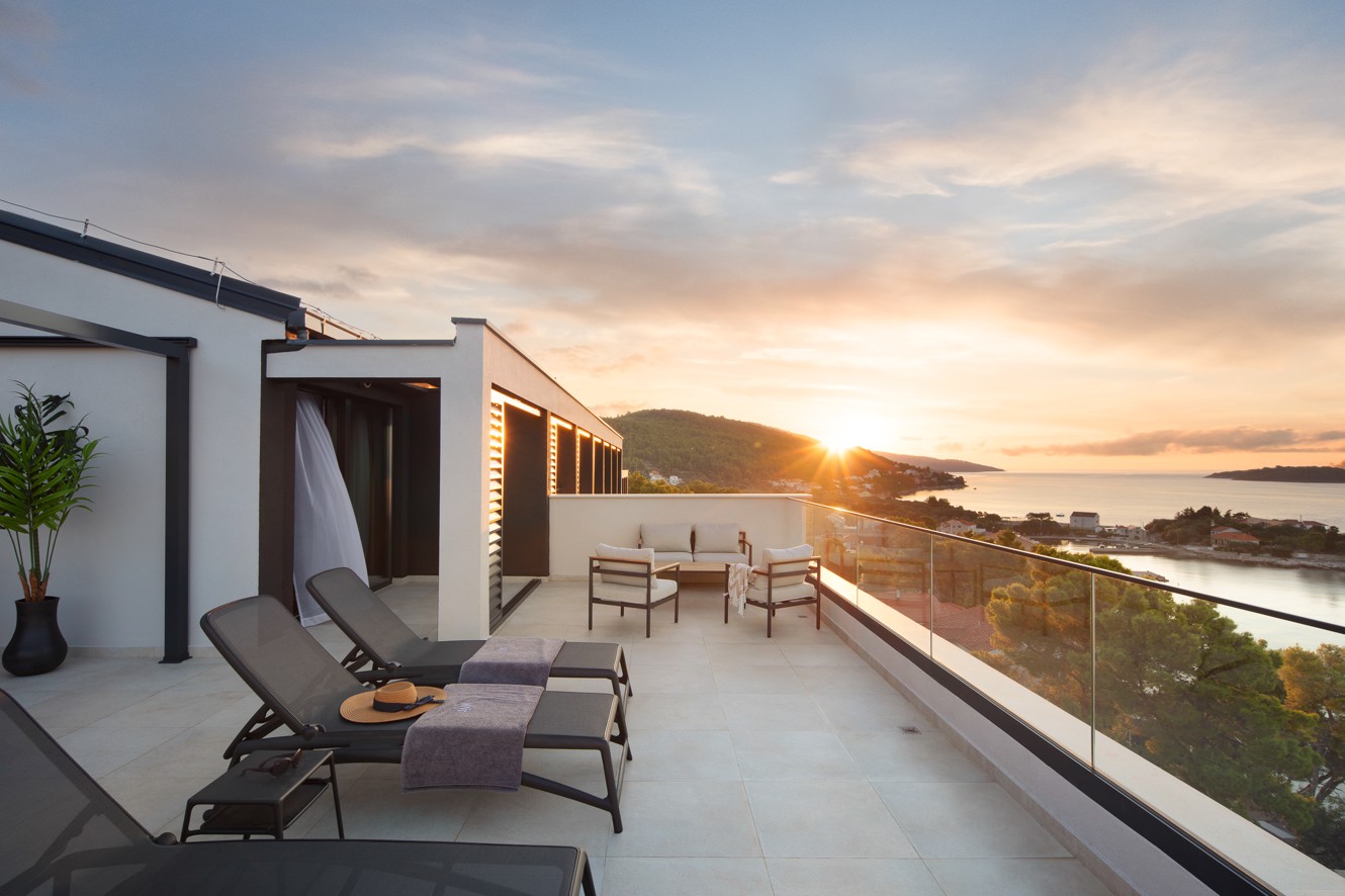 Ruim terras in Aminess Alfir Resort met ligbedden, buitenmeubilair en panoramisch uitzicht op zee bij zonsondergang