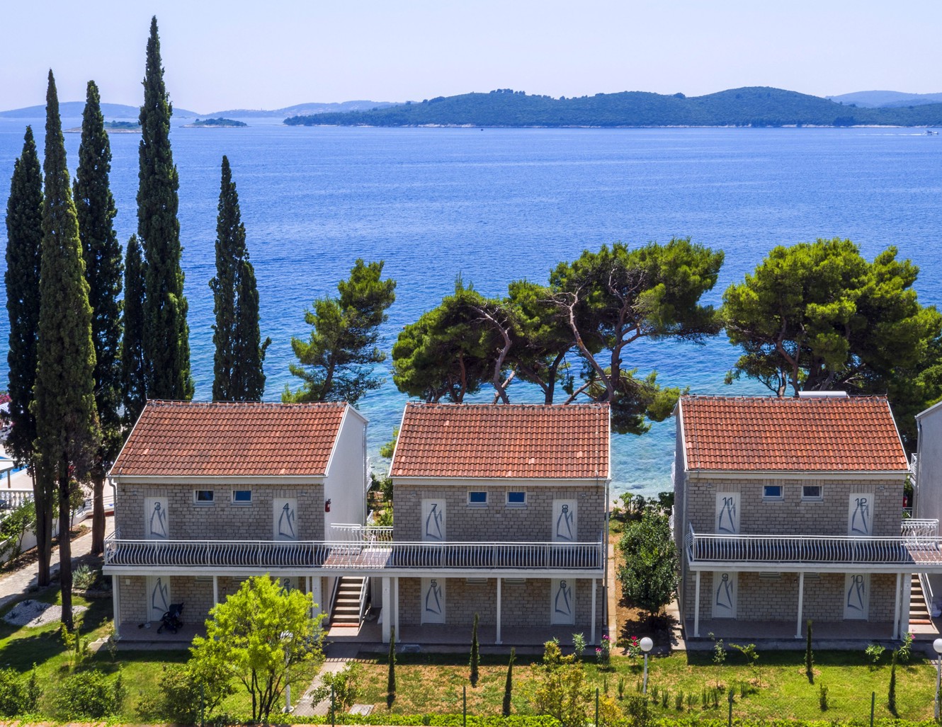 Äußere Ansicht der Gebäude des Aminess Maradiso Bellevue Village, umgeben von Bäumen, mit einem atemberaubenden Meerblick im Hintergrund auf der Halbinsel Peljesac.
