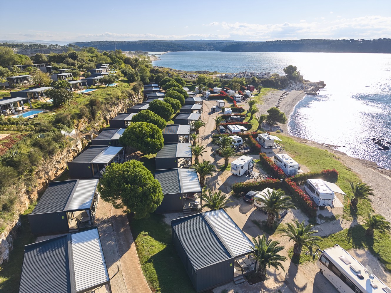 Niz modernih mobilnih kućica uz samu plažu u Aminess Planet Camping Sirena Holiday Homes, okruženih zelenilom i blizinom mora, savršenih za opuštajući odmor u prirodi