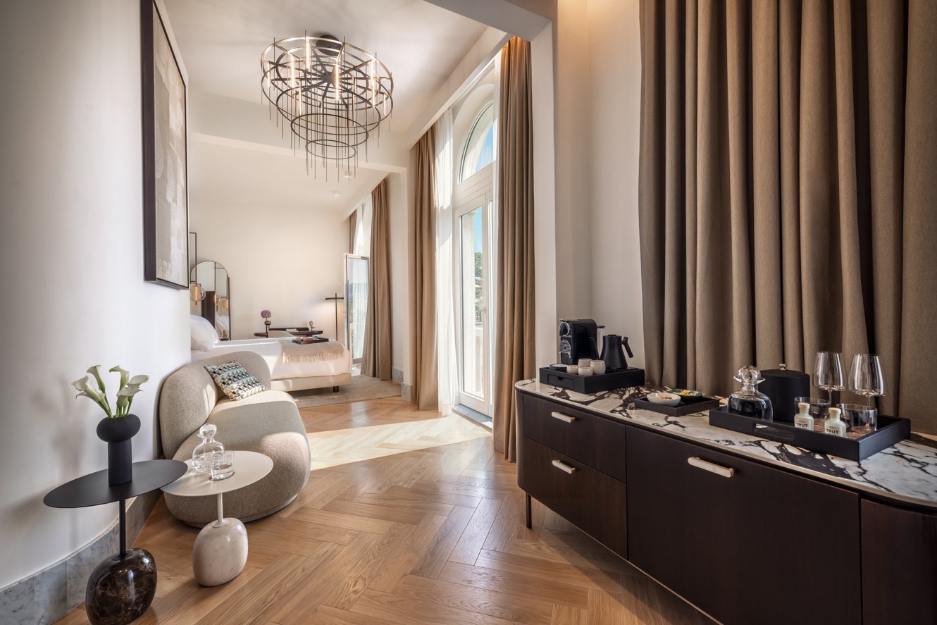 Modern Aminess hotel suite with a seating area, bed and coffee machine.