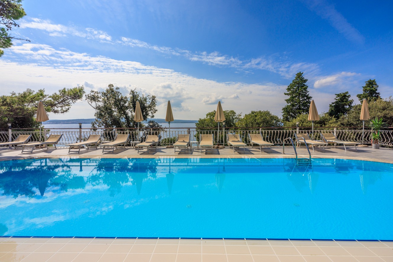 Buitenzwembad bij Mediteran Maradiso Hotel by Aminess met ligstoelen en uitzicht op zee.