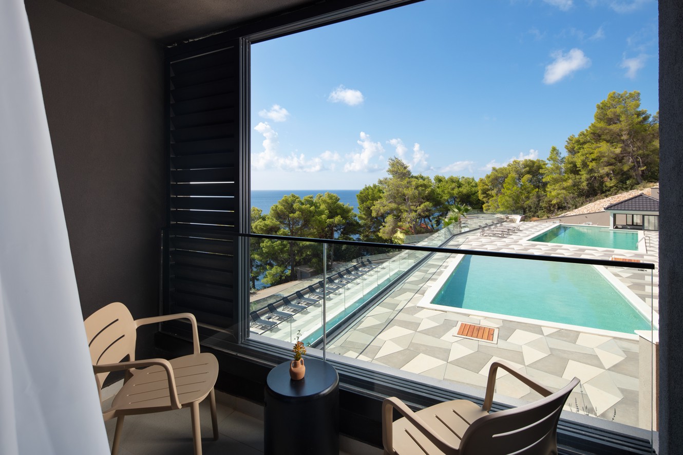 Terras van een kamer in Aminess Alfir Resort met buitenzitplaatsen en uitzicht op het zwembad en de zee in een rustige mediterrane sfeer