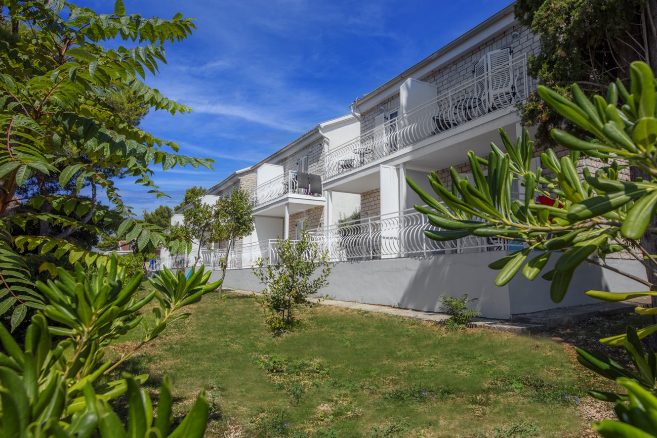 Äußeres der Aminess Bellevue Village Gebäude umgeben von üppiger grüner Vegetation.