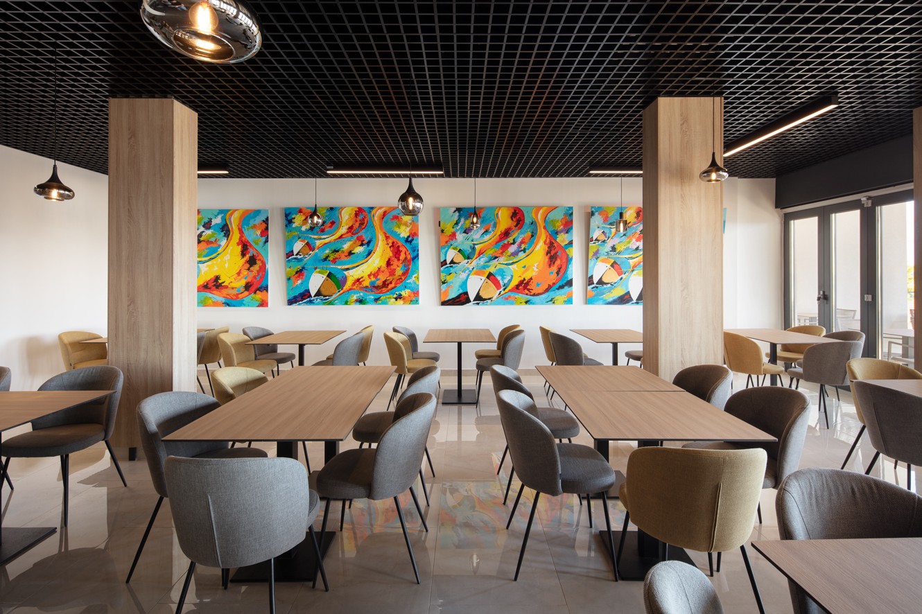 Modern restaurantinterieur in het Aminess Alfir Resort met warm houten meubilair, artistieke wanddetails en een ontspannen, gastvrije sfeer