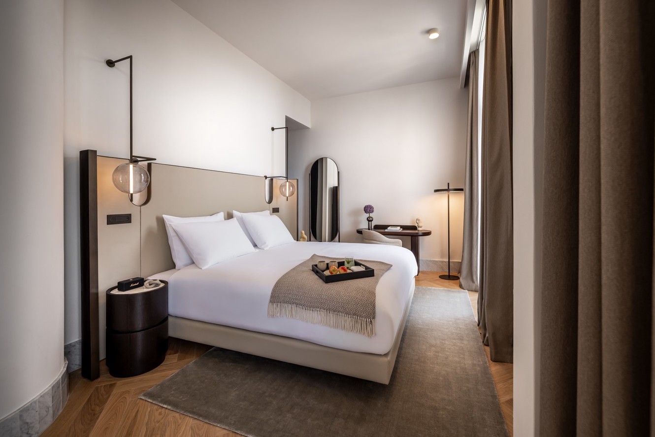 Modern Aminess hotel room with a double bed and breakfast tray.