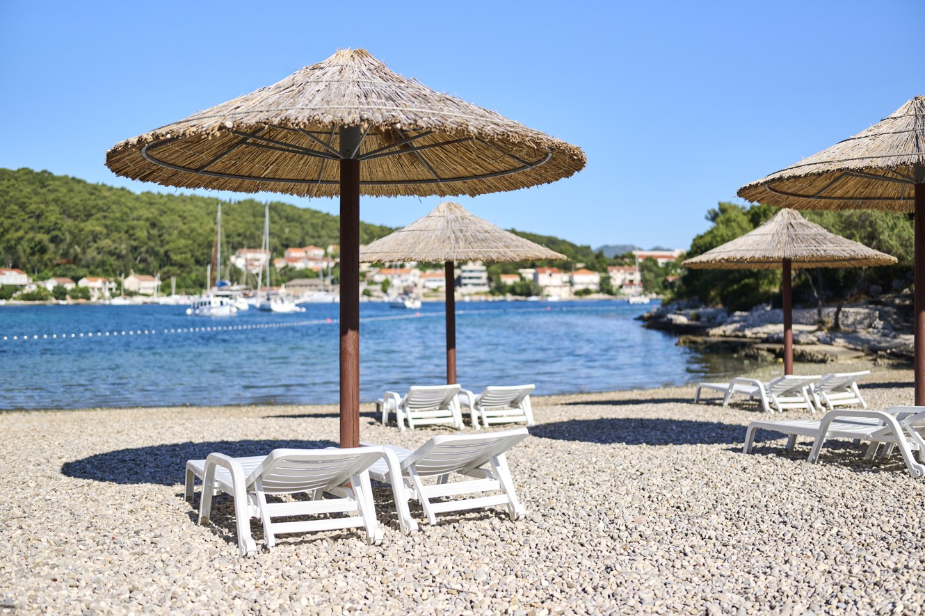 Ombrelloni di paglia e lettini sul spiaggia di ciottoli a Port9 Planet Camping by Aminess, Korcula.
