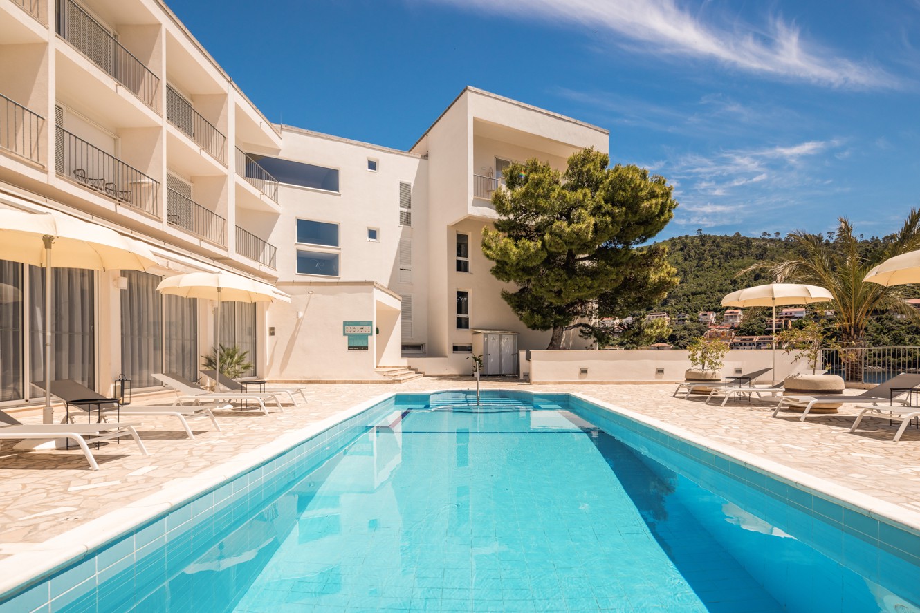View of the pool and Aminess Younique Lume Hotel, an elegant seaside retreat perfect for a relaxing stay.