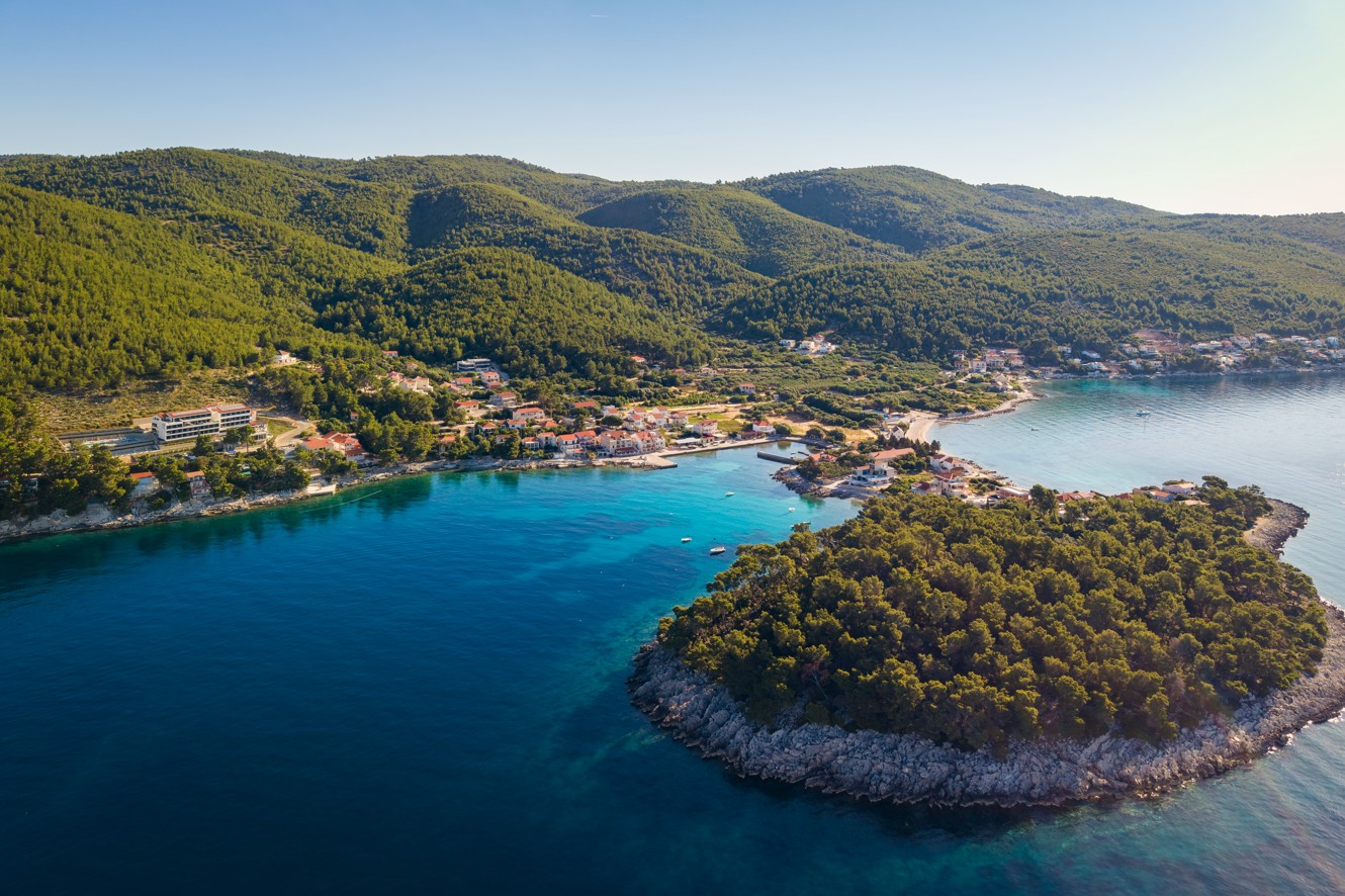 Luchtfoto van Aminess Alfir Hotel bij een turquoise baai en beboste kust.