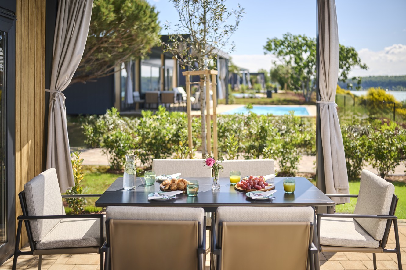 Zona pranzo esterna di una casa mobile con vista sul verde e sul mare, campeggio Aminess Sirena Novigrad.
