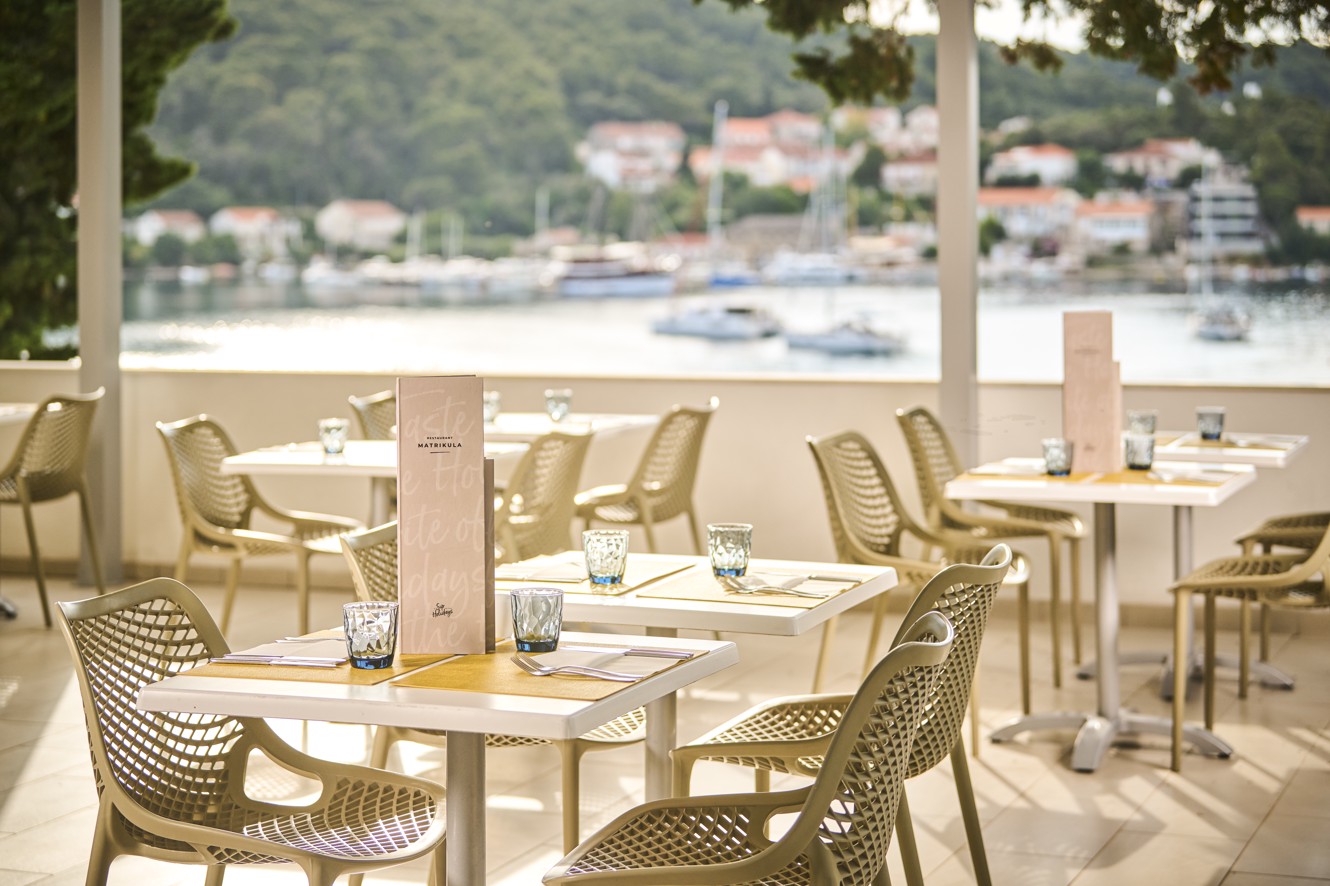 A table set with plates, cutlery, and glasses on the terrace, with a beautiful view of the surrounding area at Aminess Vival Port9 Resort in Korcula.