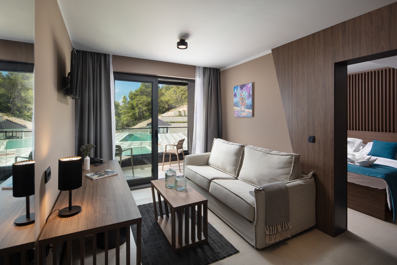 Woonruimte van een suite in Aminess Alfir Resort met comfortabele zitplaatsen, modern meubilair en toegang tot het terras met uitzicht op het zwembad