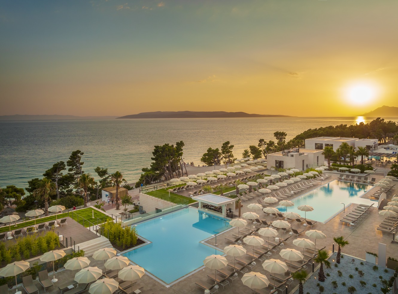 Wunderschön arrangierte Liegestühle, Swimmingpools, das Meer und der Sonnenuntergang im Aminess Laurel Khalani Hotel in Makarska.