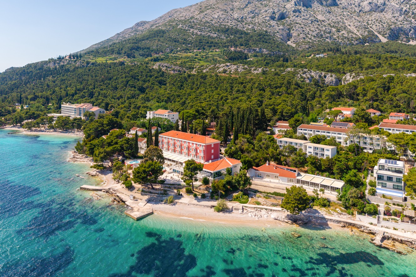 Aerial view of Bellevue Maradiso Casa by Aminess by the sea and green hillside.