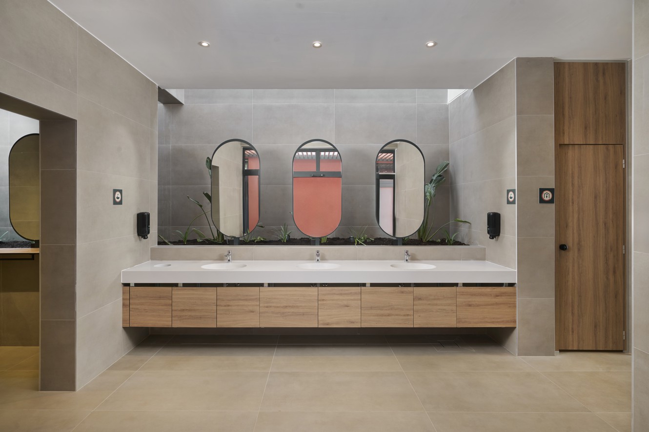 Moderne sanitaire voorziening van Aminess Atea Camping Resort op het eiland Krk met houten kasten, grote spiegels en sierplanten.