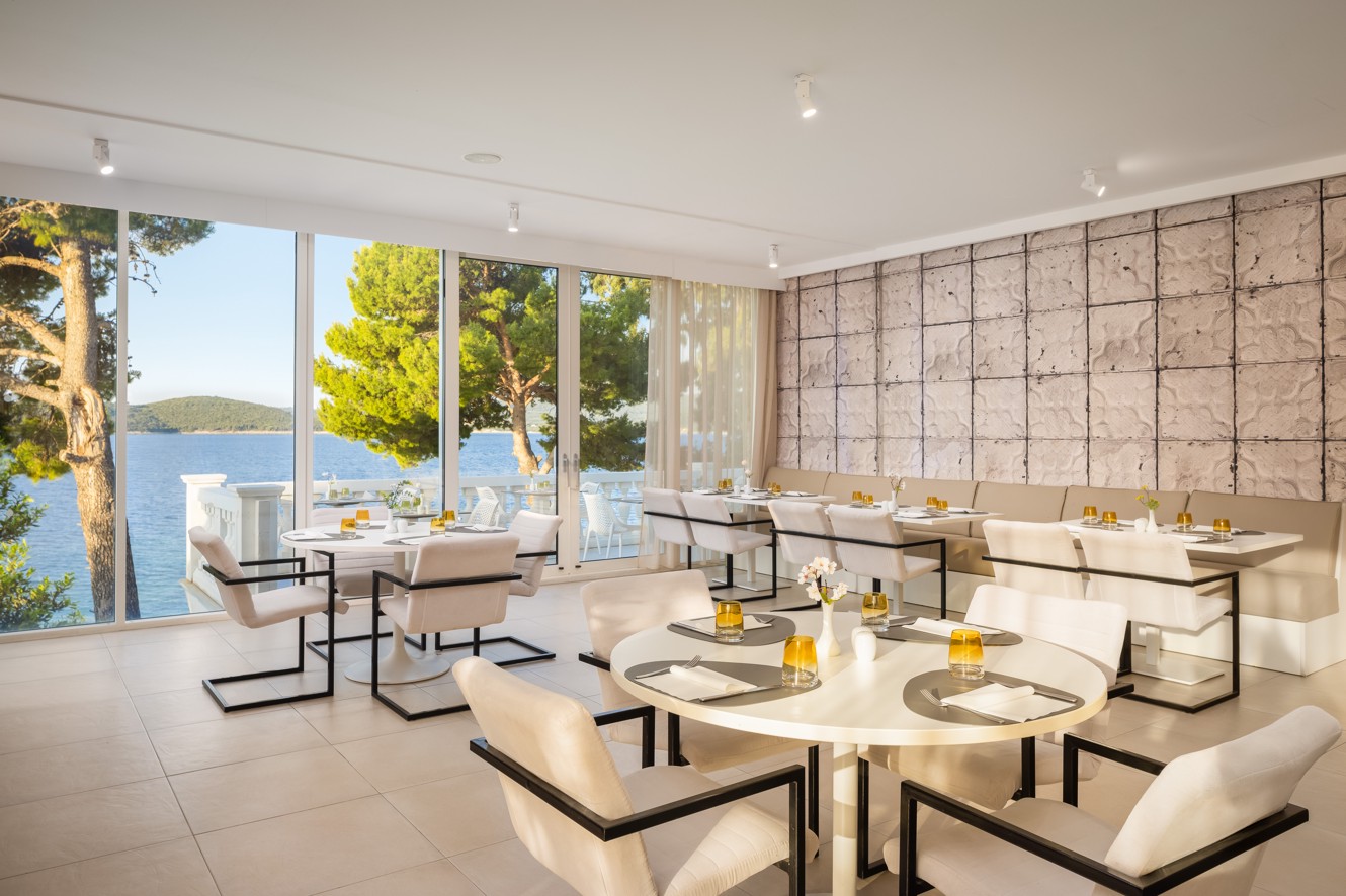 Elegant restaurant at Younique Bellevue Hotel with set tables and a sea view.