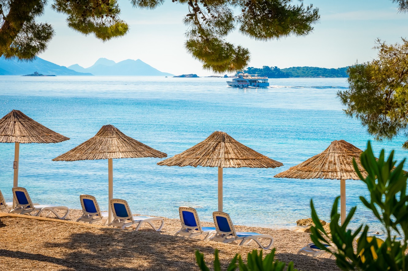 View of the beach with sun umbrellas and loungers in front of the Aminess Vival Grand Azur Hotel, Orebić.