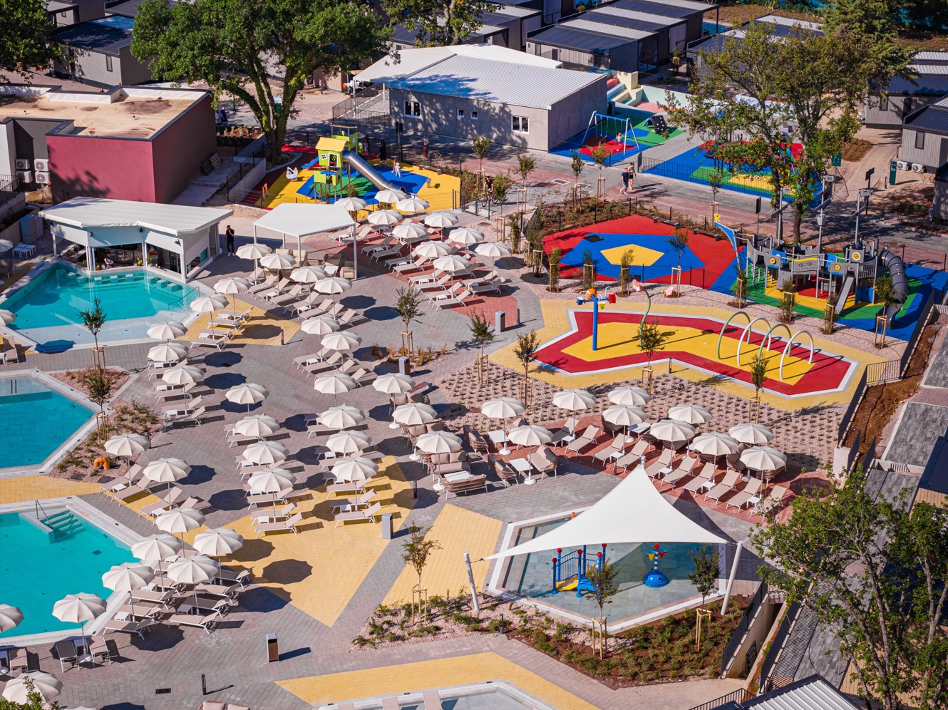 Zračni posnetek družinskega bazenskega območja z ležalniki, vodnimi igrišči in pisanimi otroškimi igrišči v Aminess Style Camping Atea Resortu.