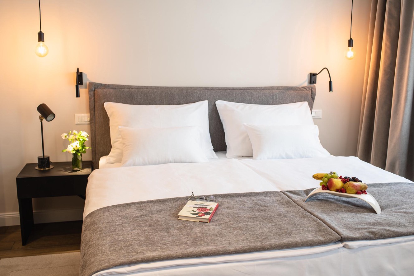 Hotel room interior with bed, welcome fruit and book