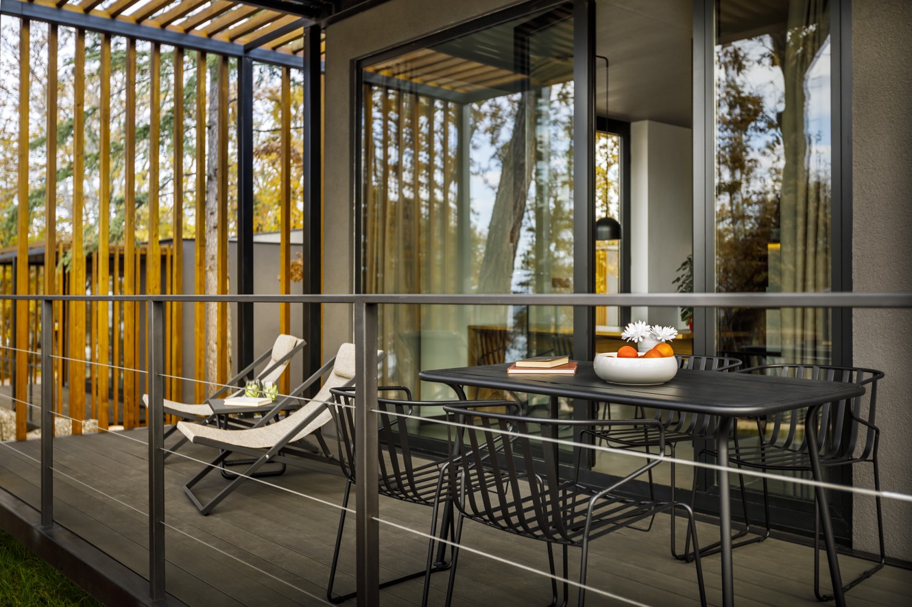 Terrace seating at Aminess Younique Gaia Green Villas, featuring lounge chairs, a dining table with fresh fruit and flowers.