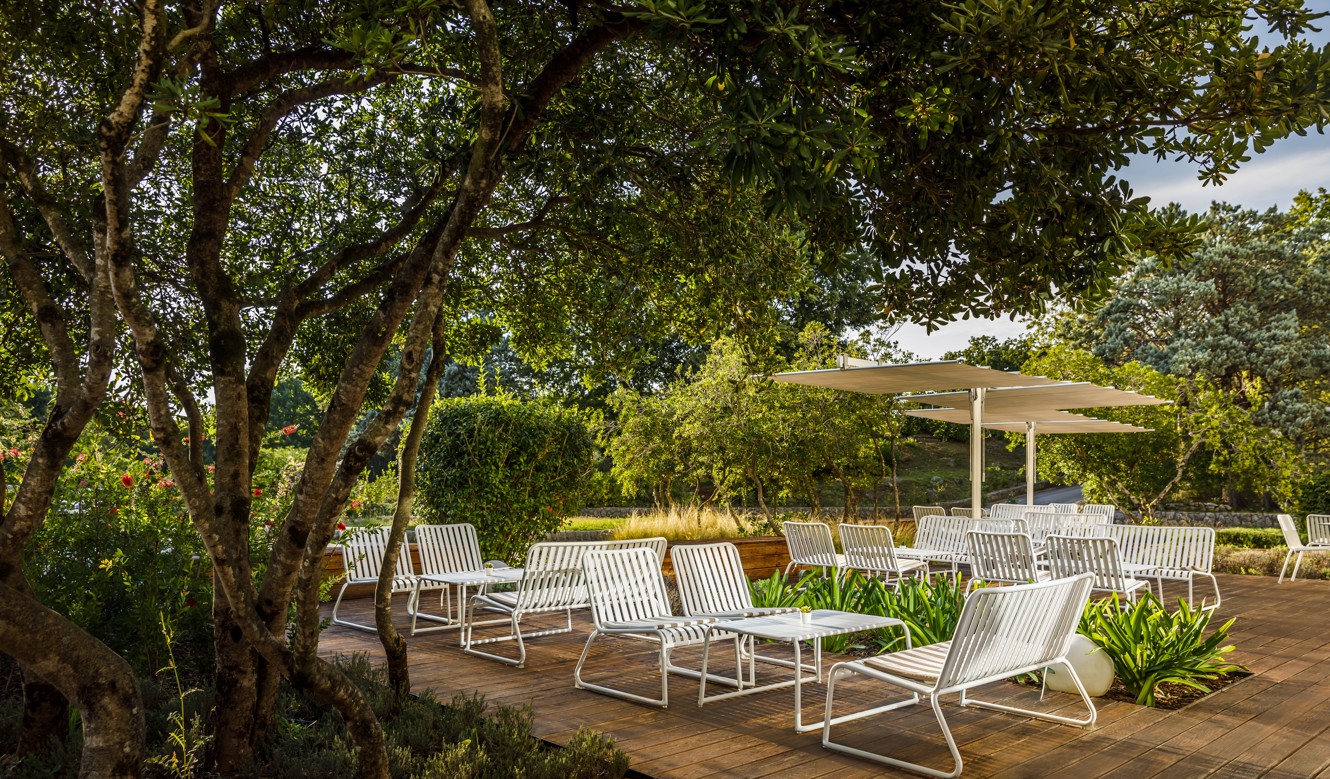 Area lounge all'aperto al bar della hall del Magal Maradiso Hotel by Aminess, circondato da una lussureggiante vegetazione.