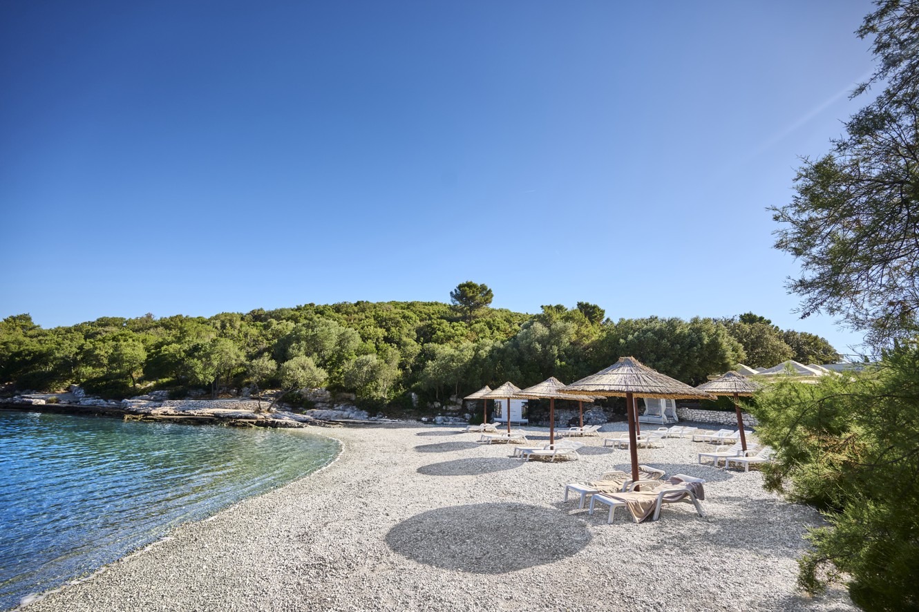 Sunloungers near the seaside within resort near Aminess Port9 Residence pebble beach.