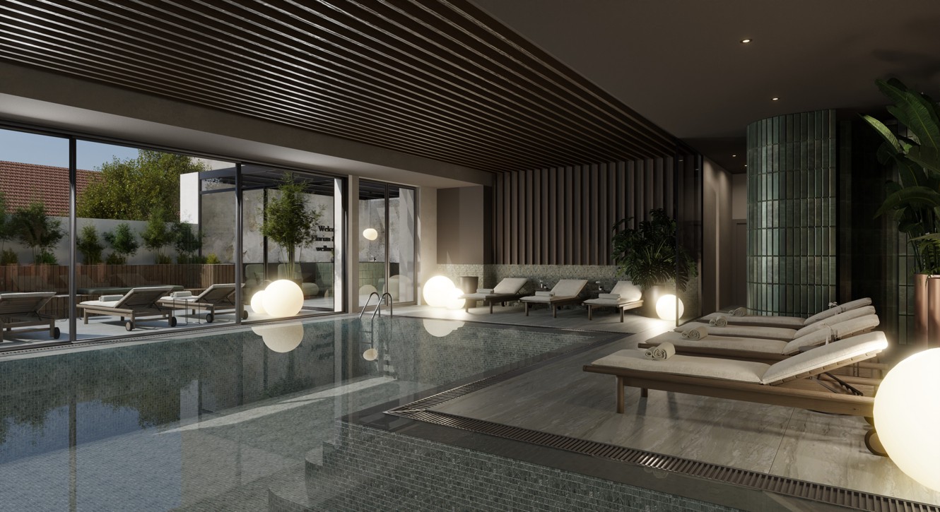 Indoor hotel pool in wellness area with loungers and outdoor view