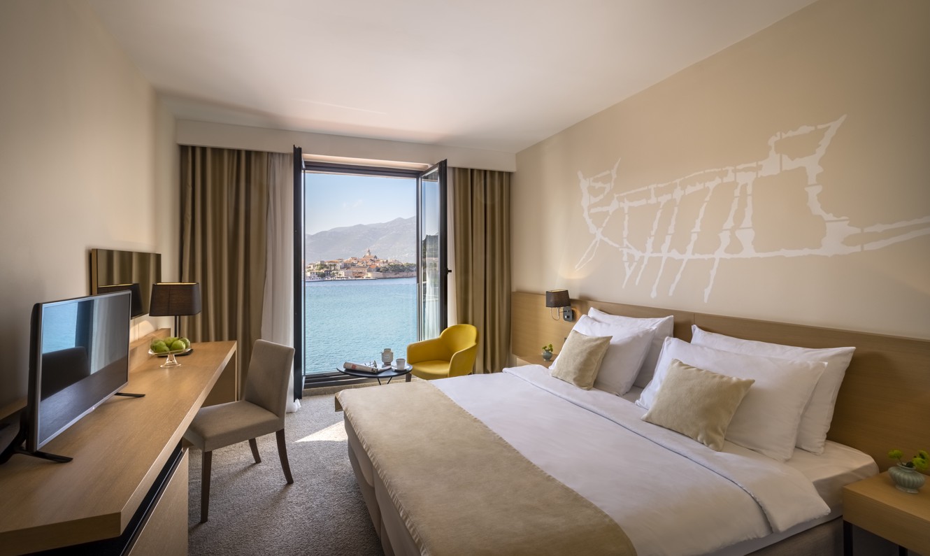 Modernes, minimalistisches Zimmer am Meer mit Fensterausblick auf die Altstadt von Korcula in Kroatien im Aminess Younique Liburna Hotel.