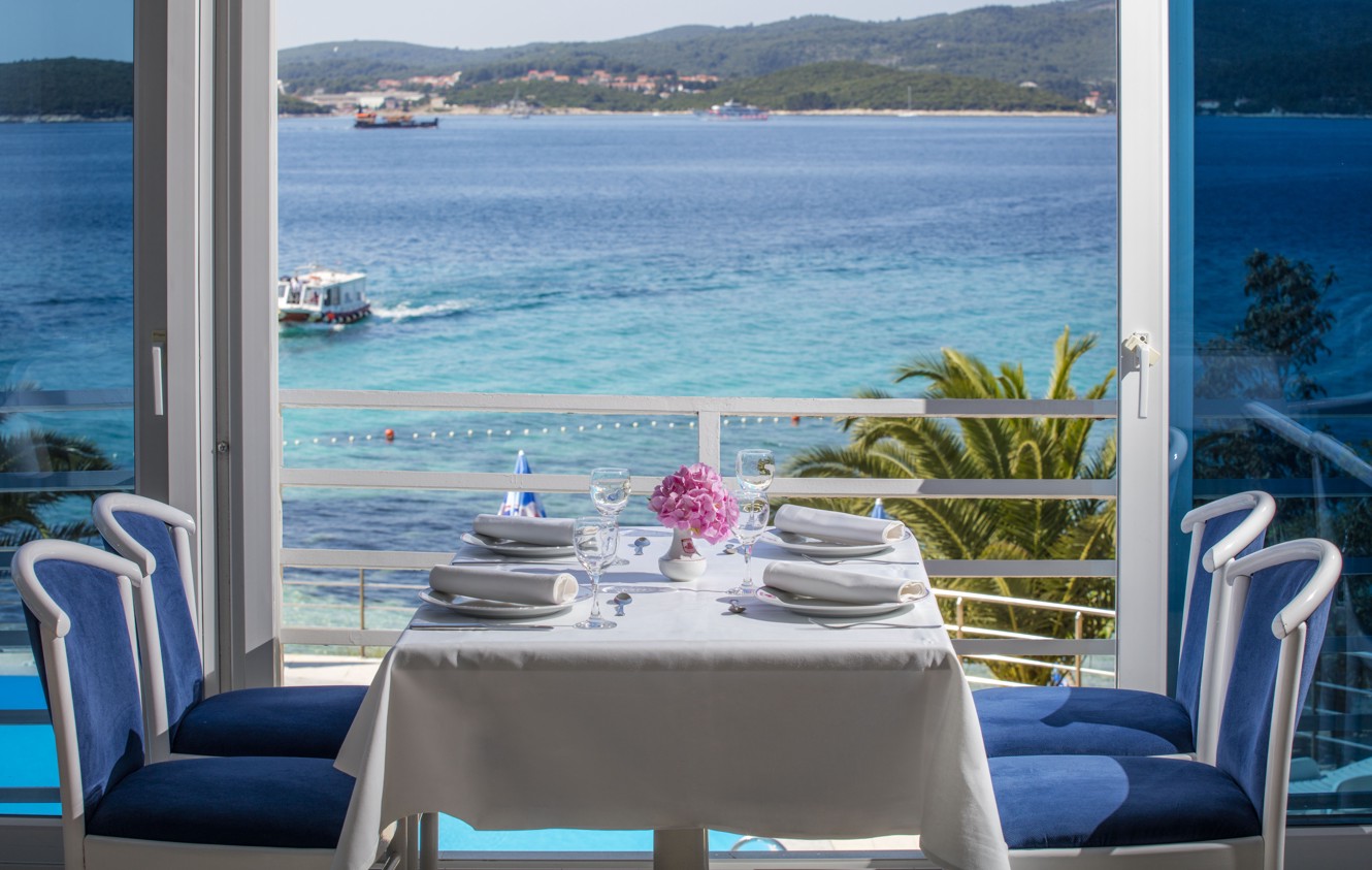 Een stel geniet van een romantische dinerervaring bij zonsondergang op het terras van het nabijgelegen Maradiso Orsan Hotel by Aminess, met uitzicht op de Adriatische Zee.