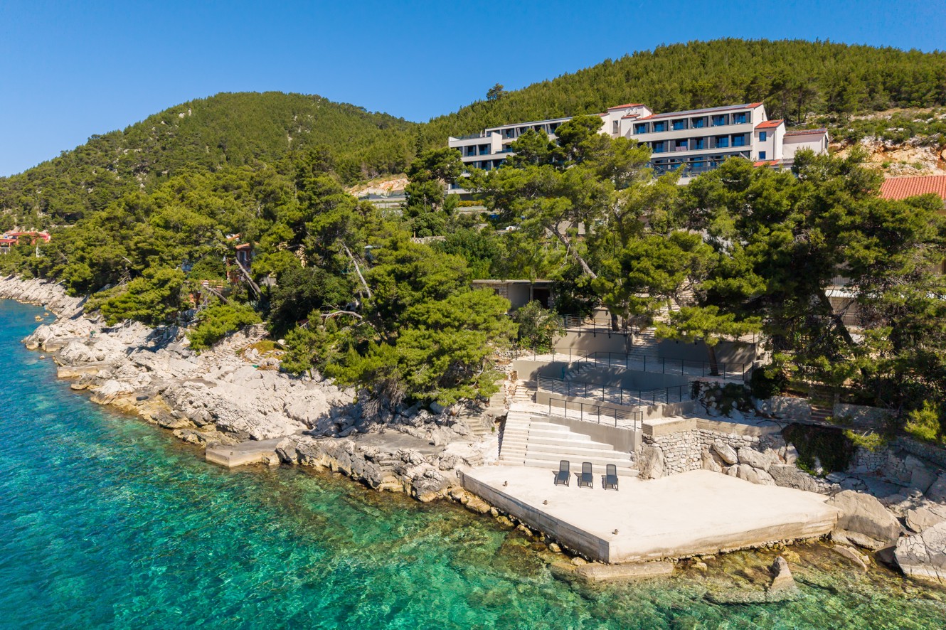 Luchtfoto van Aminess Alfir Hotel boven een rotsstrand en turquoise zee.