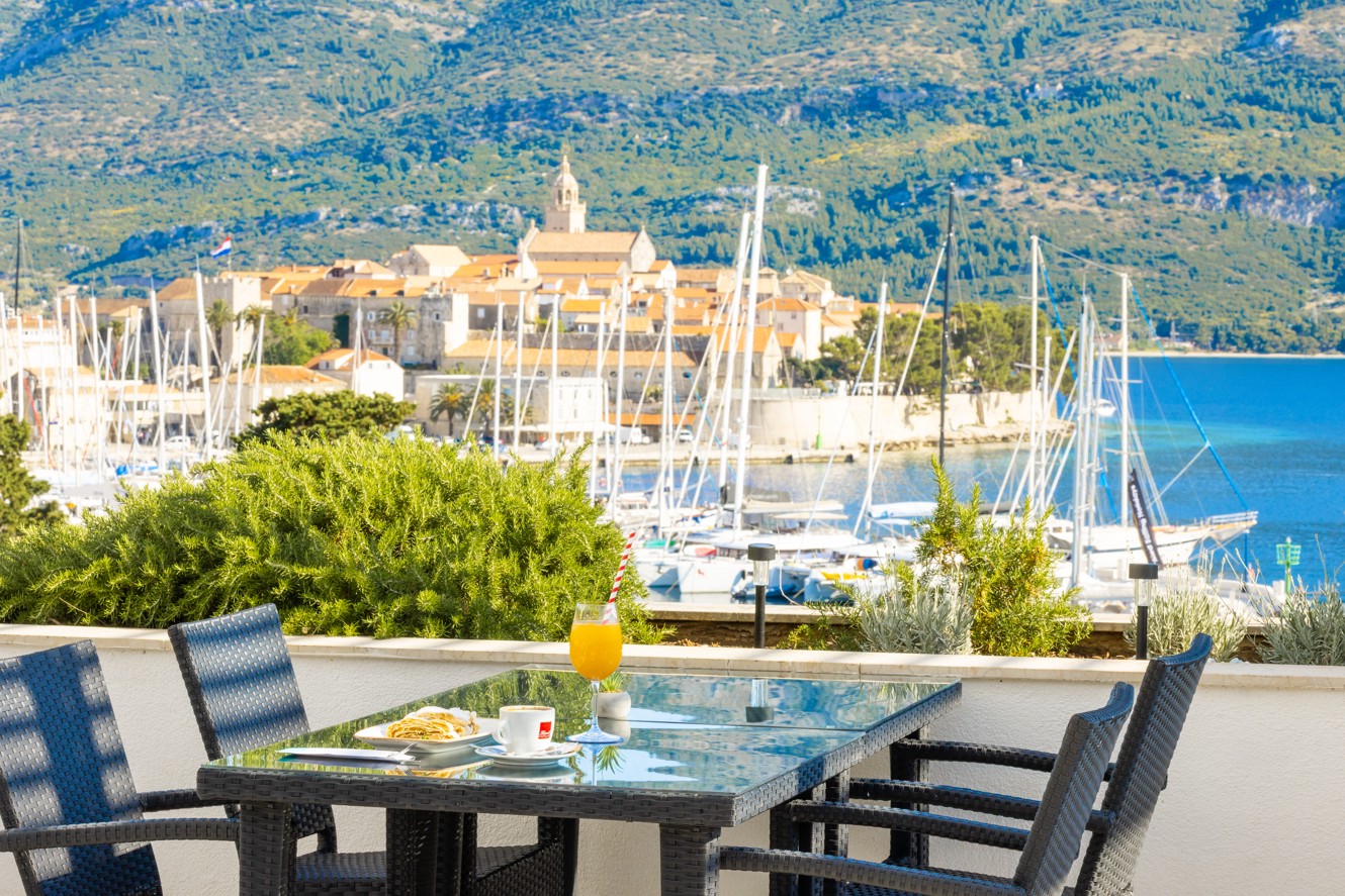 Bar uz bazen u Maradiso Marko Polo by Aminess u Korčuli s povišenim pogledom na marinu, zgrade grada s crvenim krovovima i bujno zelenilo.