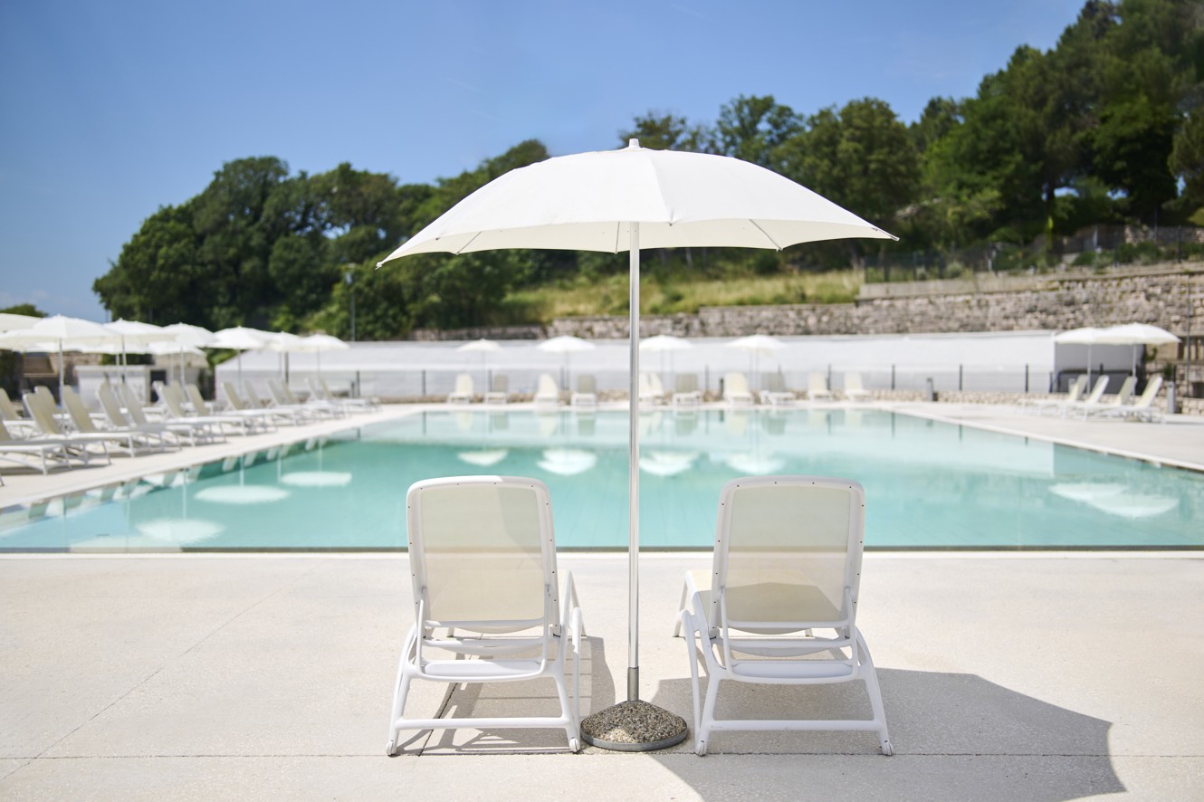 Piscina esterna dell’hotel Aminess Lišanj con lettini e ombrellone, immersa nel verde.