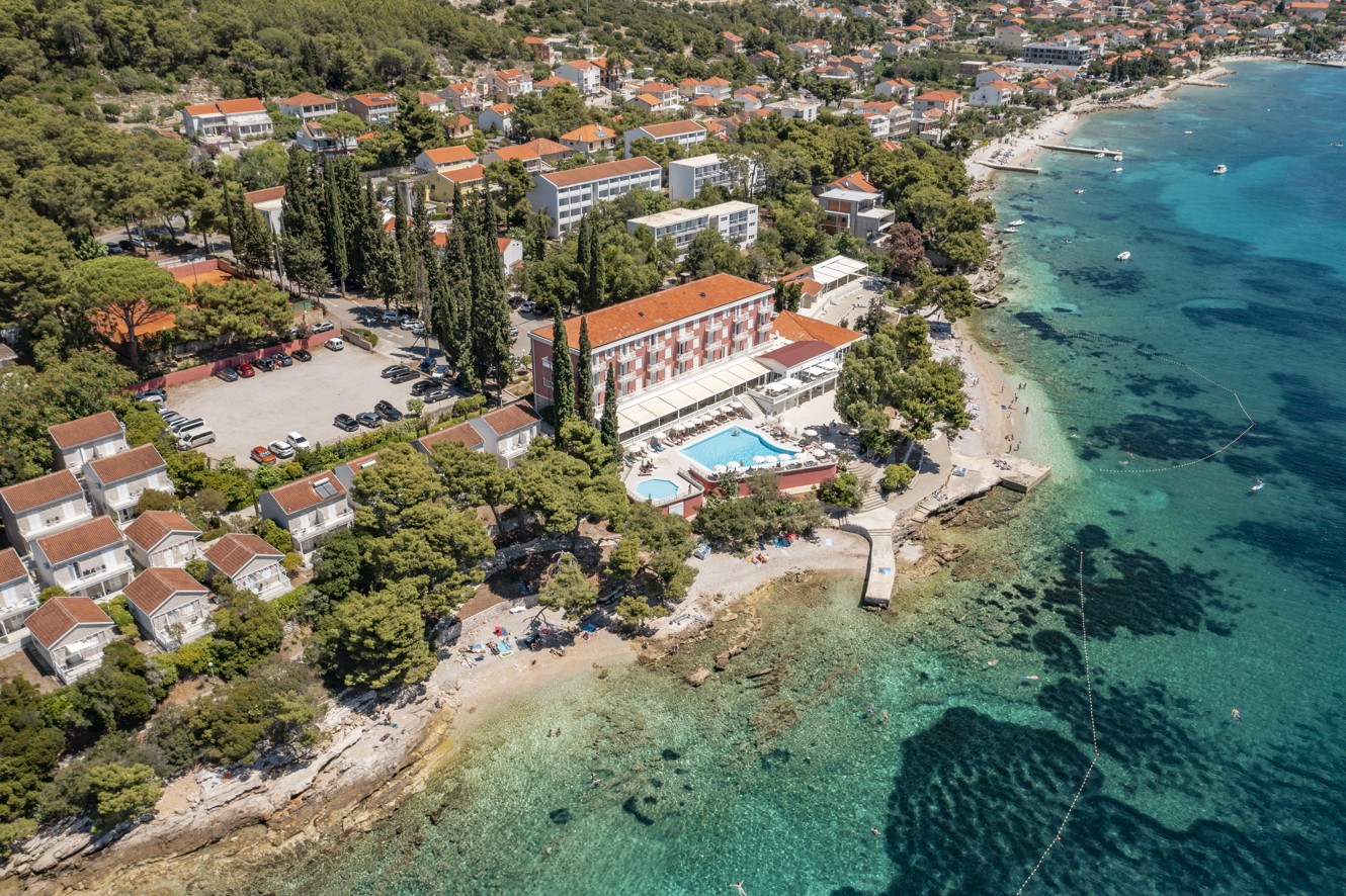 Ein Vogelperspektive auf das Aminess Bellevue Village, eingebettet in üppiges Grün, mit einem privaten Strand und direktem Meereszugang