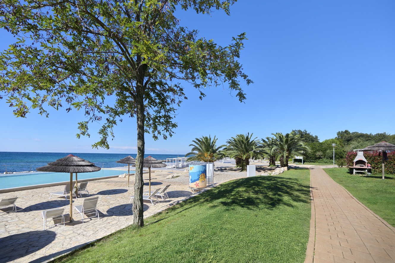 Promenade am Strand im Aminess Planet Camping Maravea Resort, umgeben von Grünflächen – ein perfekter Ort für einen entspannten Spaziergang