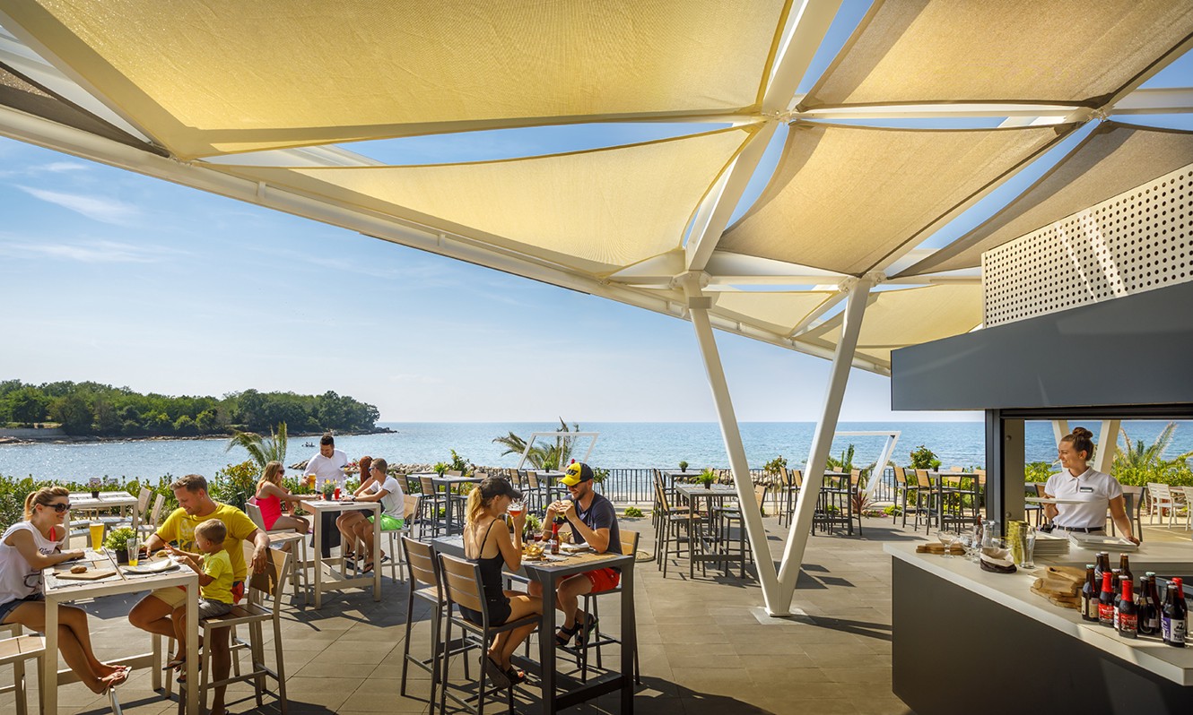 Gäste genießen eine Mahlzeit in einem Restaurant im Aminess Planet Camping Maravea Resort, Novigrad Kroatien