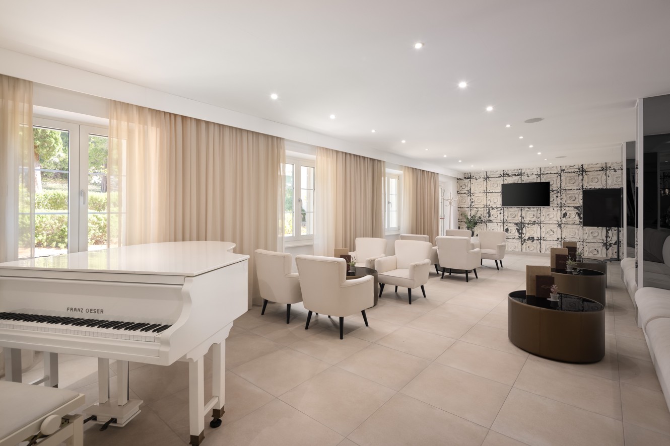 Bar Noir lounge at Younique Bellevue Hotel by Aminess with a white piano and armchairs.