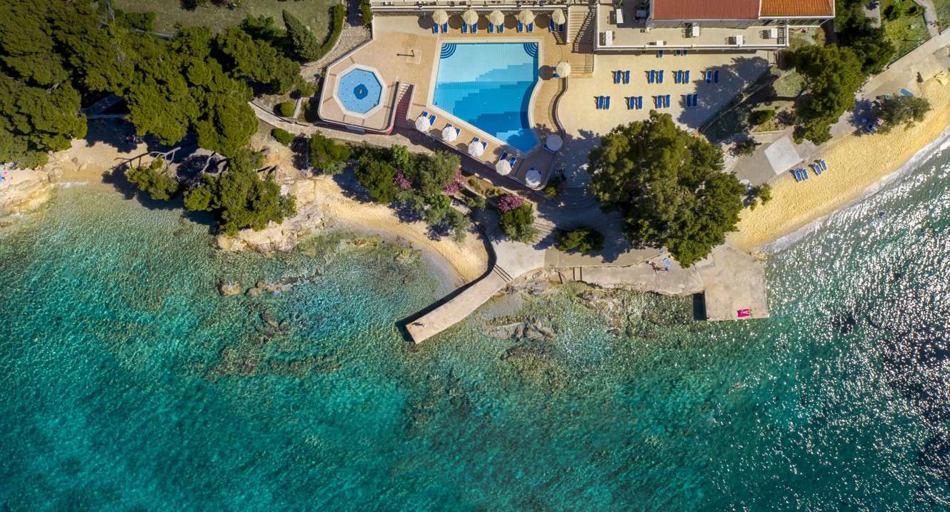 Eine sonnenverwöhnte Poolterrasse in der Nähe von Aminess Maradiso Casa Bellevue in Kroatien, mit atemberaubendem Meerblick und komfortablen Liegestühlen zum Entspannen.