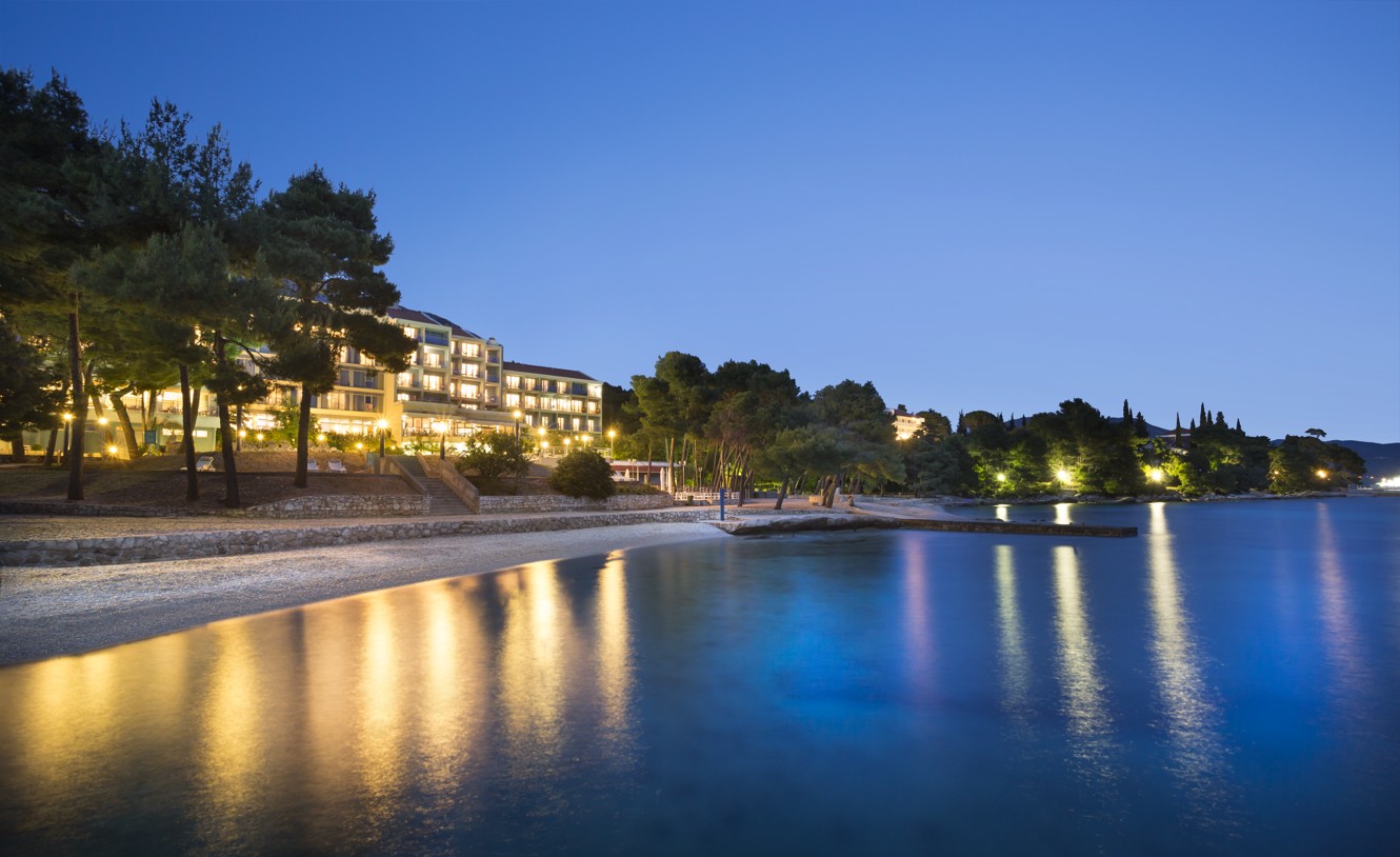 A picturesque image of  Aminess Vival Grand Azur Hotel nestled along a serene beach at dusk.
