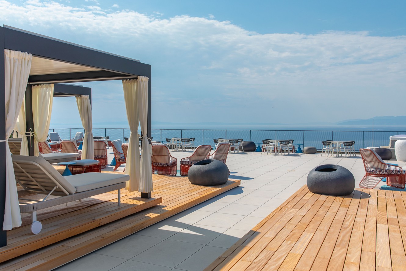 Sunčana terasa Aminess Vollo Residences s ležaljkama i pogledom na more.