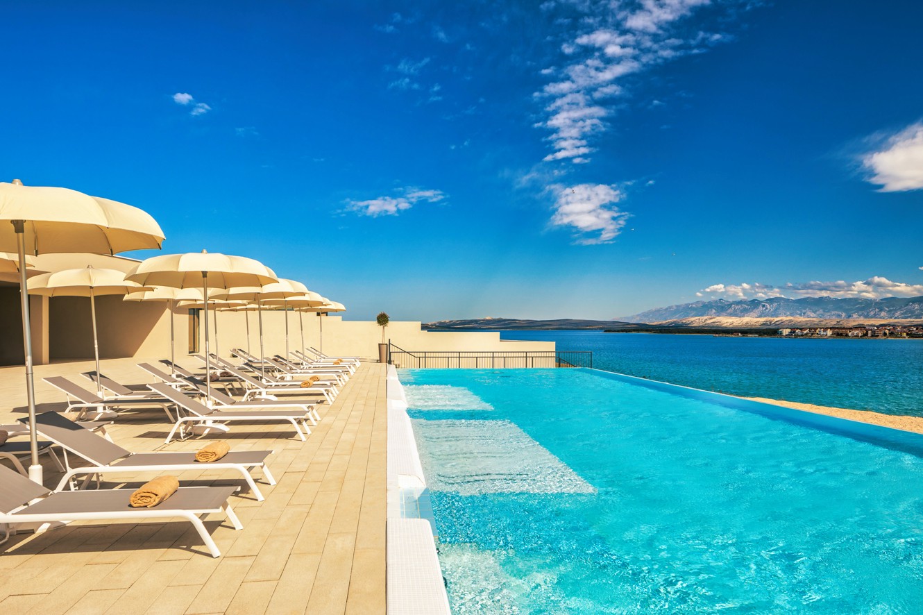 Deck chairs and umbrellas lined up next to the relax pool with sea view at Aminess Style Camping Avalona resort.