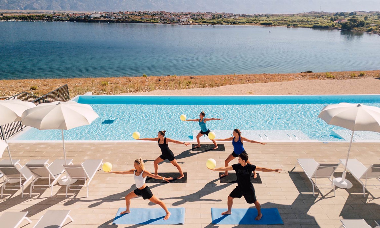 Gruppo di persone che fanno yoga vicino alla Relax pool presso il resort Aminess Style Camping Avalona.