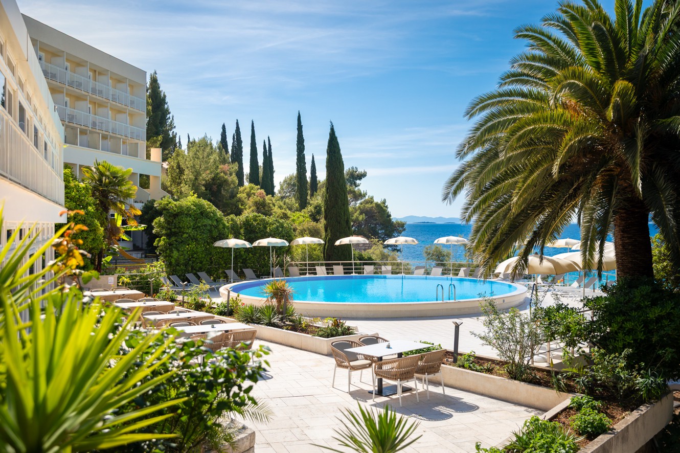 Pool at Orsan Maradiso Hotel by Aminess with a palm tree and sea view.