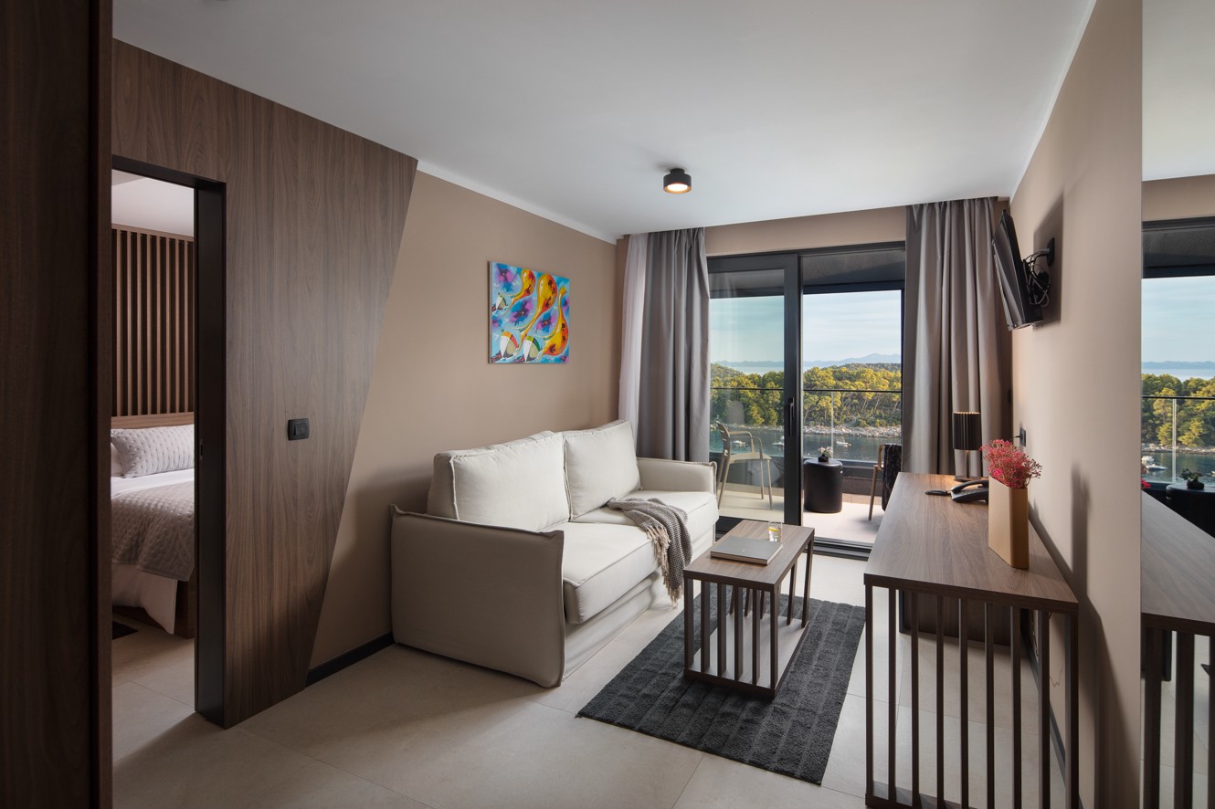 Woonruimte van een suite in Aminess Alfir Resort met comfortabele zitplaatsen, modern meubilair en toegang tot het terras met zeezicht